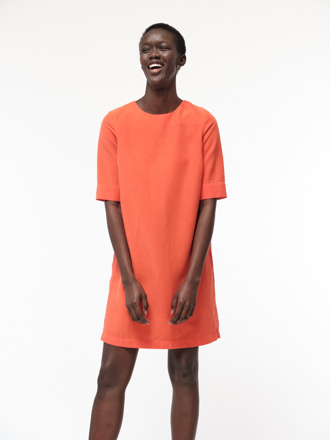 lachende schöne Frau trägt nachhaltiges bio-faires kurzes oranges Kleid von Lanius